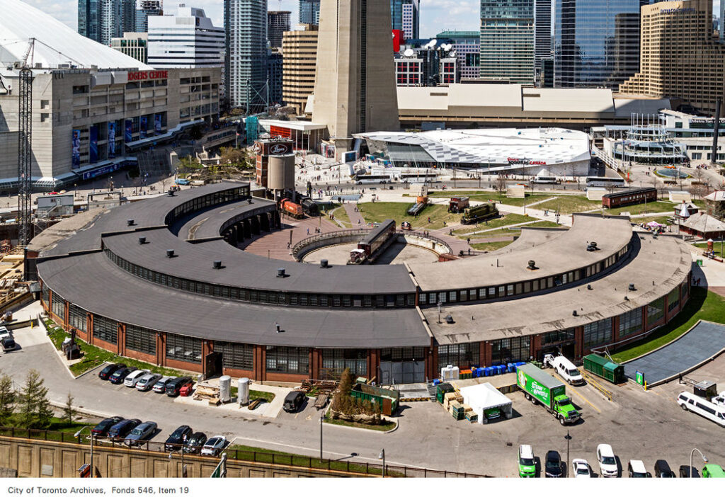 Aerial view of the John Street Roundhouse taken from the south end.  Steam Whistle Brewery is located in the segment on the right with the lighter roof.  The Toronto Railway Museum occupies the darker roofed segment on the left. Photo taken on May 2, 2015 by Vik Pahwa, Fonds 546, Item 19, City of Toronto Archives www.toronto.ca/archives